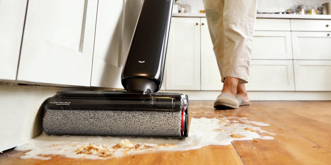 Person cleaning spilled liquid on wooden floor with vacuum