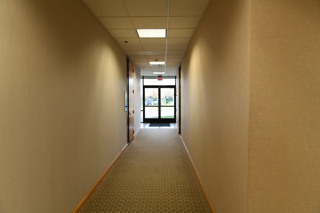 Long, empty hallway with beige walls and a door.